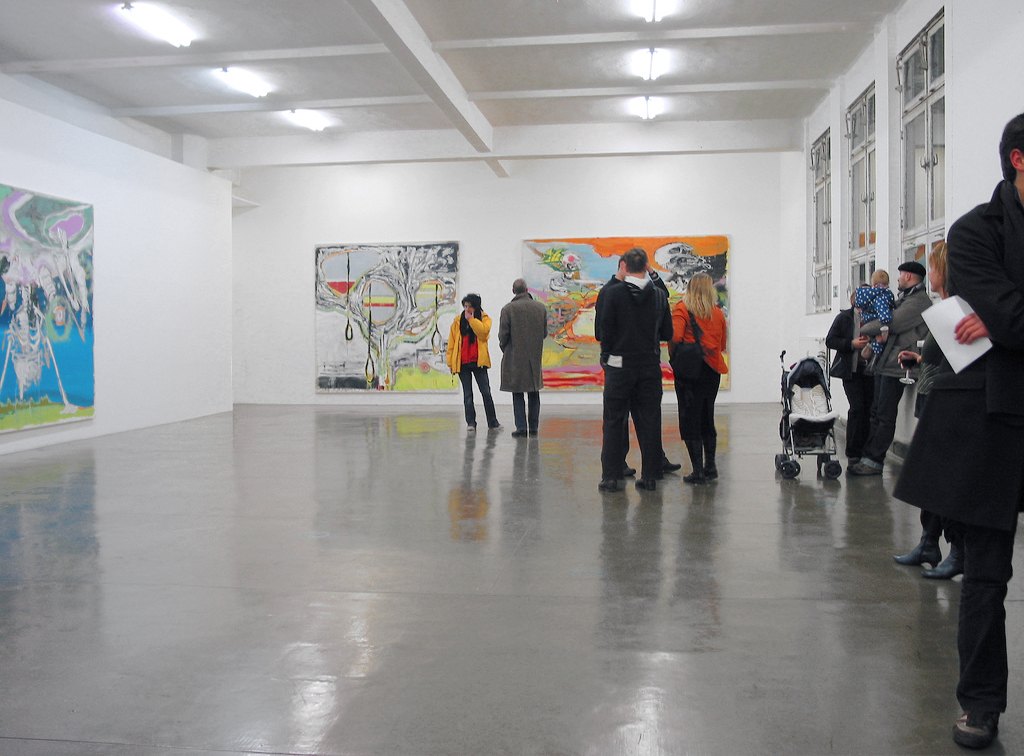 Besucher betrachten in der 2yk Galerie in Berlin Gemälde des Künstlers Michael Markwick.